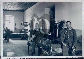 Recto carte postale Offiers et soldats Wehrmacht lisant livre sur leurs lits dans un dortoir avec un drapeau à croix gammée nazi accroché